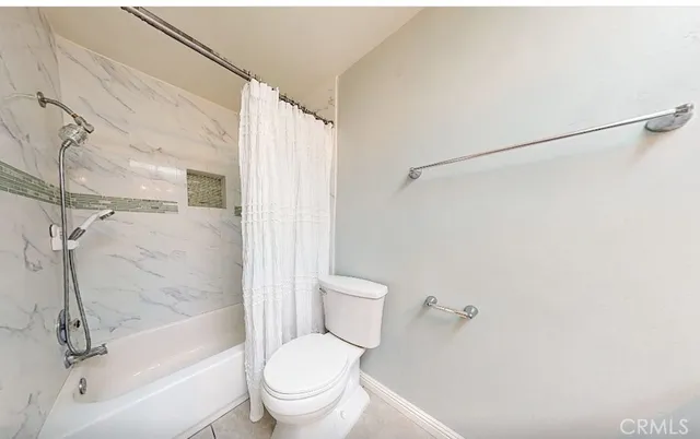 a bathroom with a granite countertop bathtub shower sink vanity and toilet