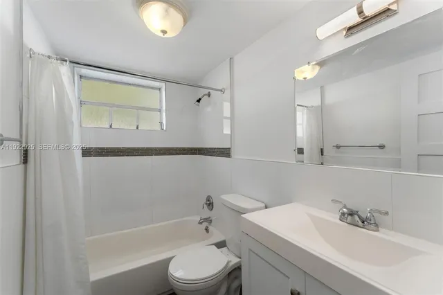 a bathroom with a bathtub shower sink vanity and toilet