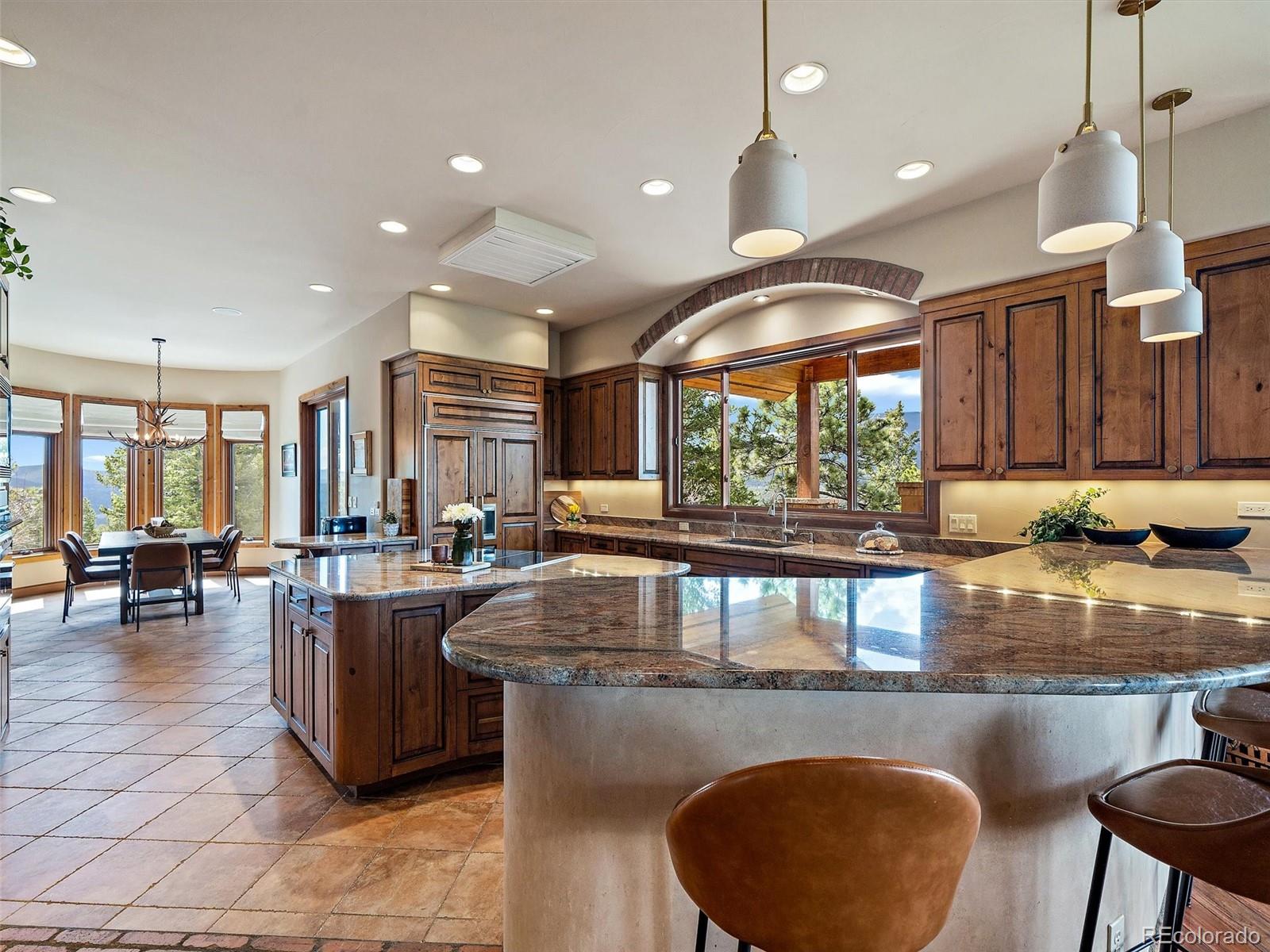 32024 Snowshoe Road Evergreen, CO 80439 - Photo 12 of 50 a kitchen with stainless steel appliances granite countertop a stove a refrigerator a sink a dining table and chairs with wooden floor