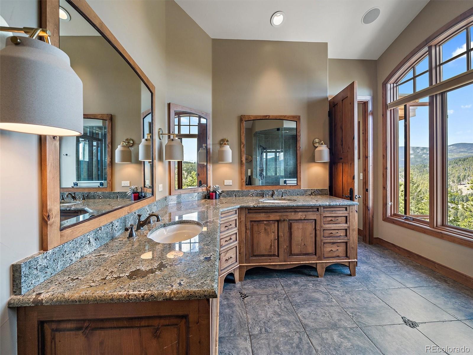 32024 Snowshoe Road Evergreen, CO 80439 - Photo 28 of 50 a large bathroom with a granite countertop sink and a large mirror