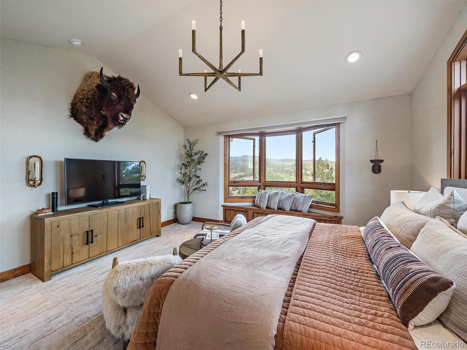 32024 Snowshoe Road Evergreen, CO 80439 - Photo 30 of 50 a bedroom with bed a flat tv screen and a large window