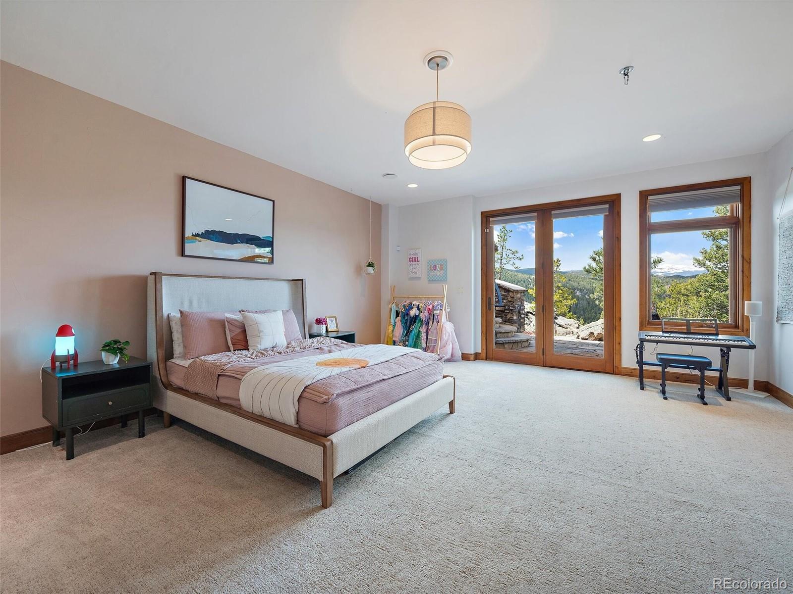 32024 Snowshoe Road Evergreen, CO 80439 - Photo 36 of 50 a spacious bedroom with a bed and a large window