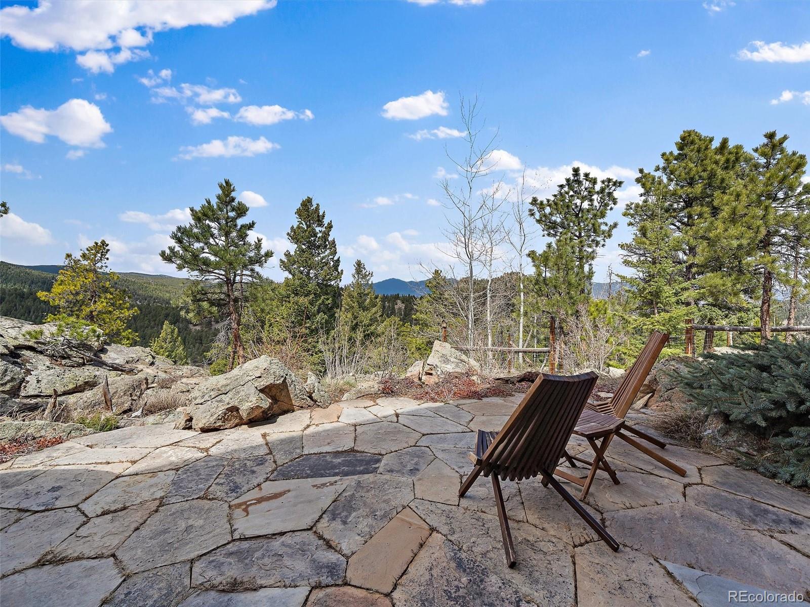 32024 Snowshoe Road Evergreen, CO 80439 - Photo 37 of 50 a backyard of a house with table and chairs