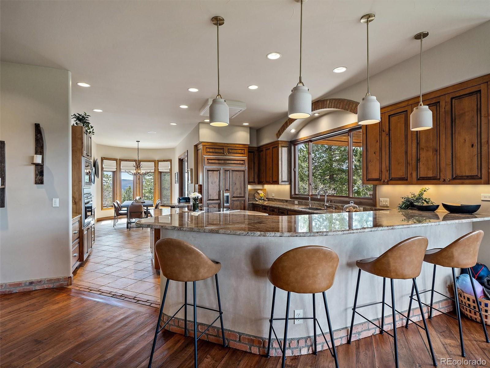 32024 Snowshoe Road Evergreen, CO 80439 - Photo 10 of 50 a kitchen with stainless steel appliances granite countertop a stove a refrigerator a kitchen island a dining table and chairs with wooden floor
