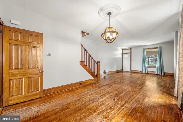 a view of an empty room with wooden floor and window