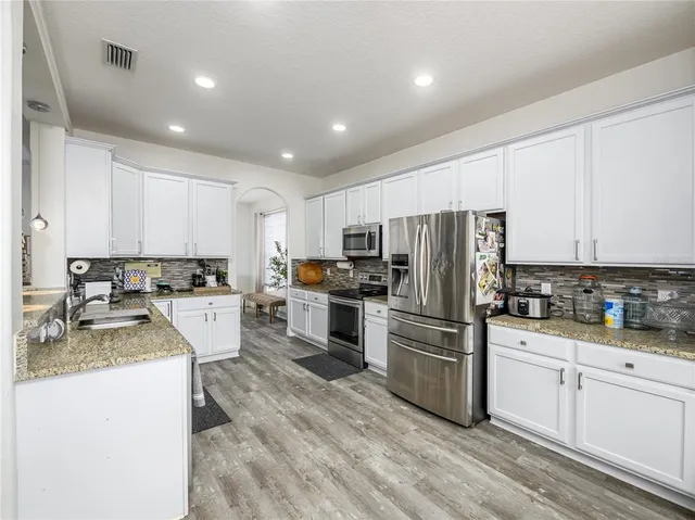 a kitchen with a refrigerator a stove top oven a sink and cabinets