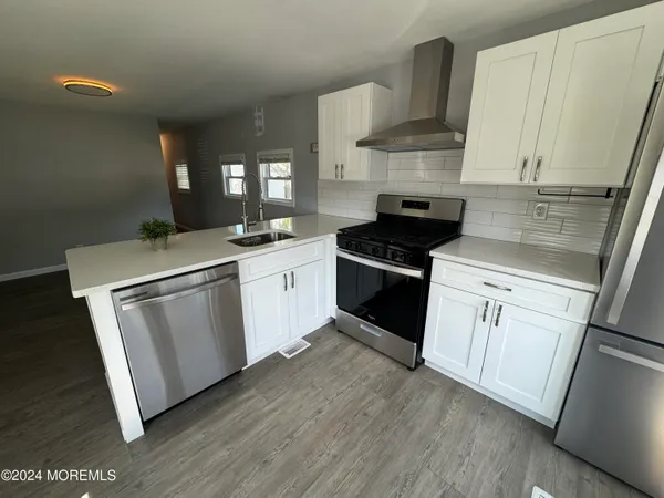 a kitchen with white cabinets appliances and wooden floor