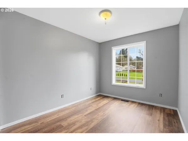 an empty room with wooden floor and window