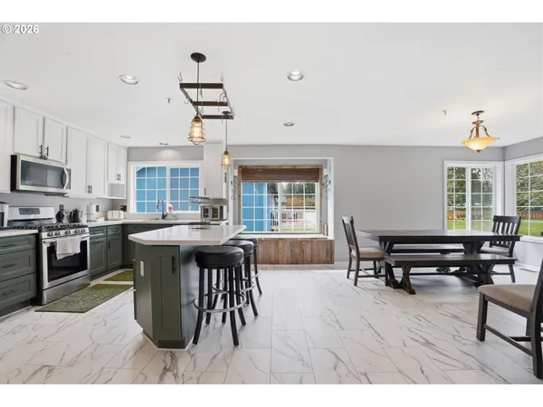 a open kitchen with stainless steel appliances granite countertop a stove top oven a sink a dining table and chairs with wooden floor