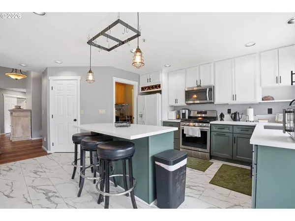 a kitchen with stainless steel appliances kitchen island a table chairs sink and cabinets