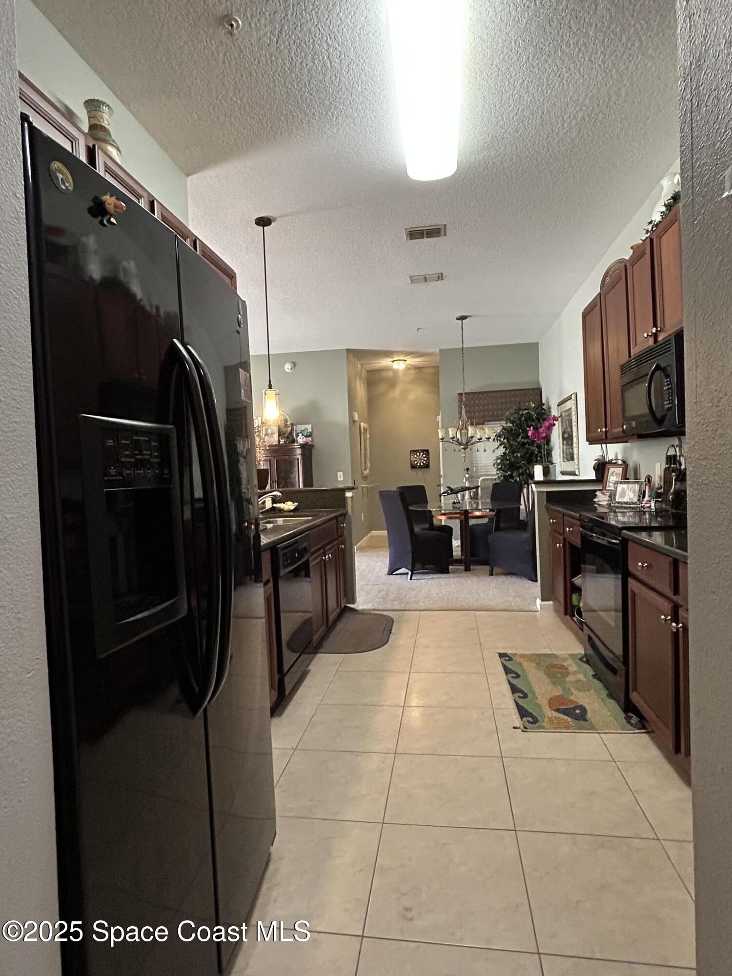 4067 Meander Place, Unit 204 Rockledge, FL 32955 - Photo 5 of 17 a kitchen with stainless steel appliances kitchen island granite countertop a refrigerator and a stove top oven