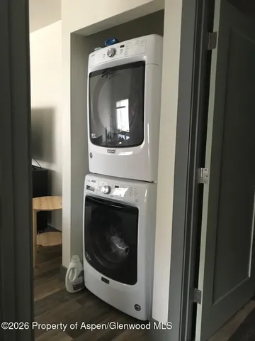 a view of a hallway with wooden floor and a small refrigerator