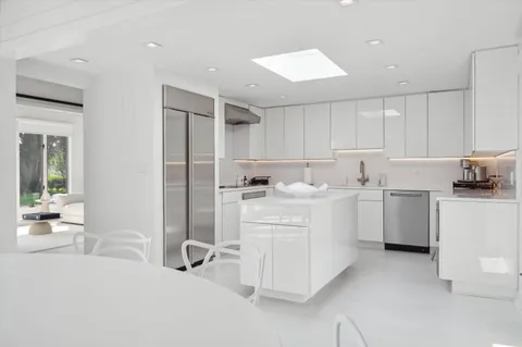 a large white kitchen with a stove a sink dishwasher and a refrigerator