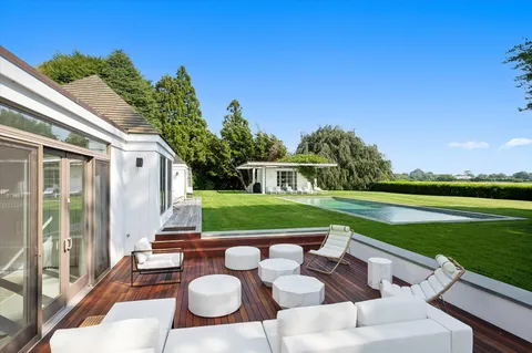 a view of swimming pool with lawn chairs and plants