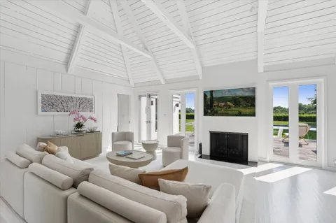 a living room with furniture a flat screen tv a fireplace and a ceiling fan