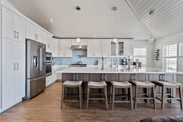 a kitchen with stainless steel appliances granite countertop a dining table chairs refrigerator and sink