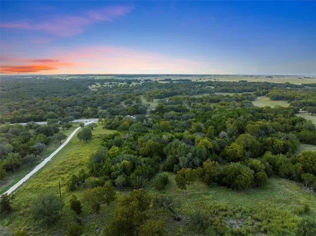 an aerial view of residential houses with outdoor space and trees