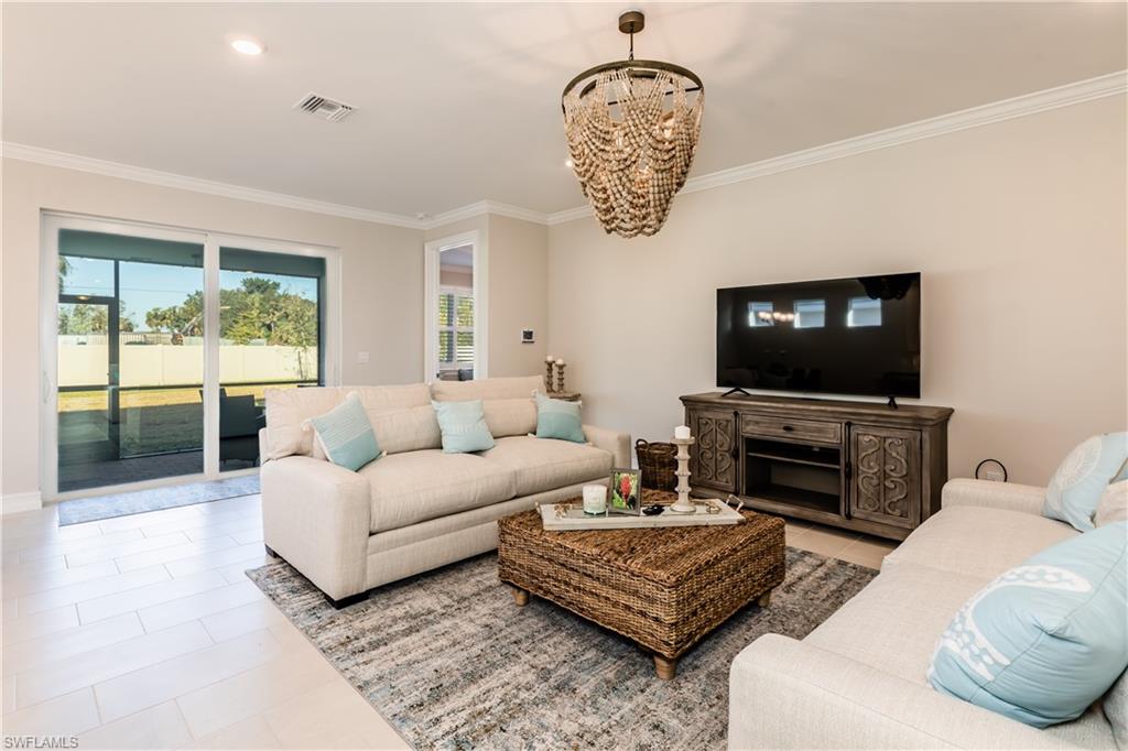 267 Tamarindo Lane Naples, FL 34114 - Photo 4 of 18 a living room with furniture a flat screen tv and a chandelier
