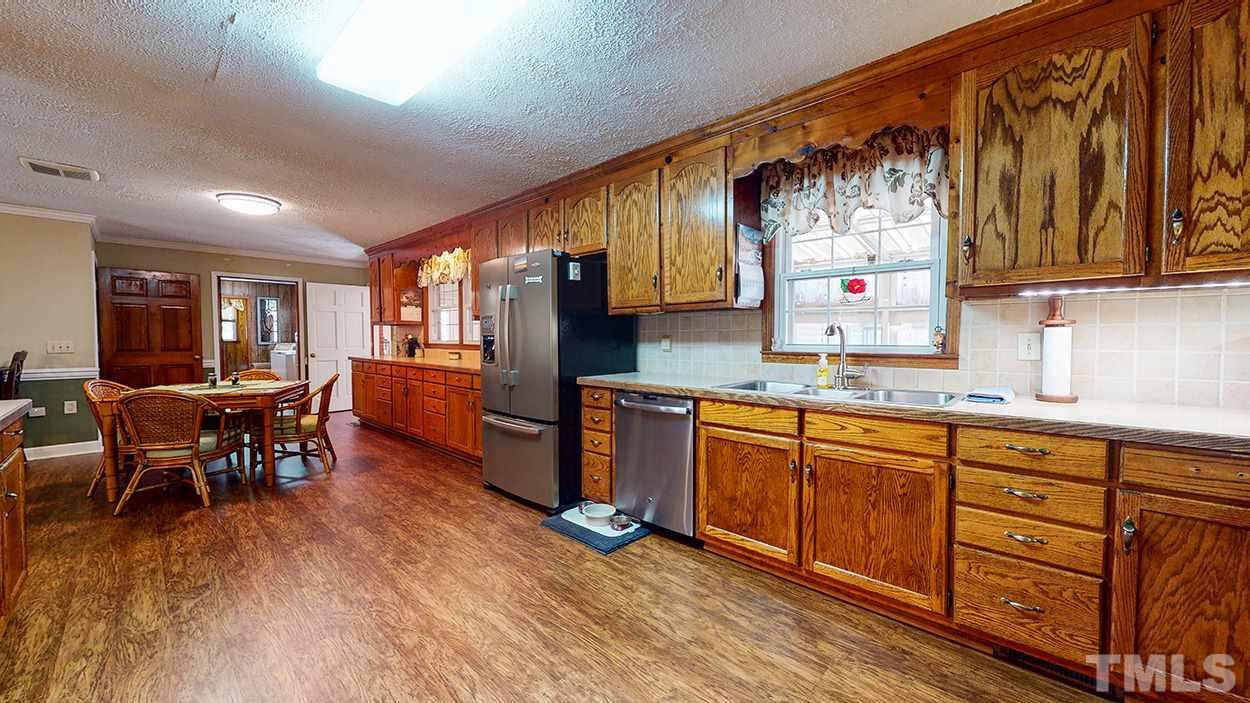 3111 Old Allensville Road Roxboro, NC 27574 - Photo 6 of 17 a kitchen with stainless steel appliances granite countertop a refrigerator a sink dishwasher a dining table and chairs with wooden floor