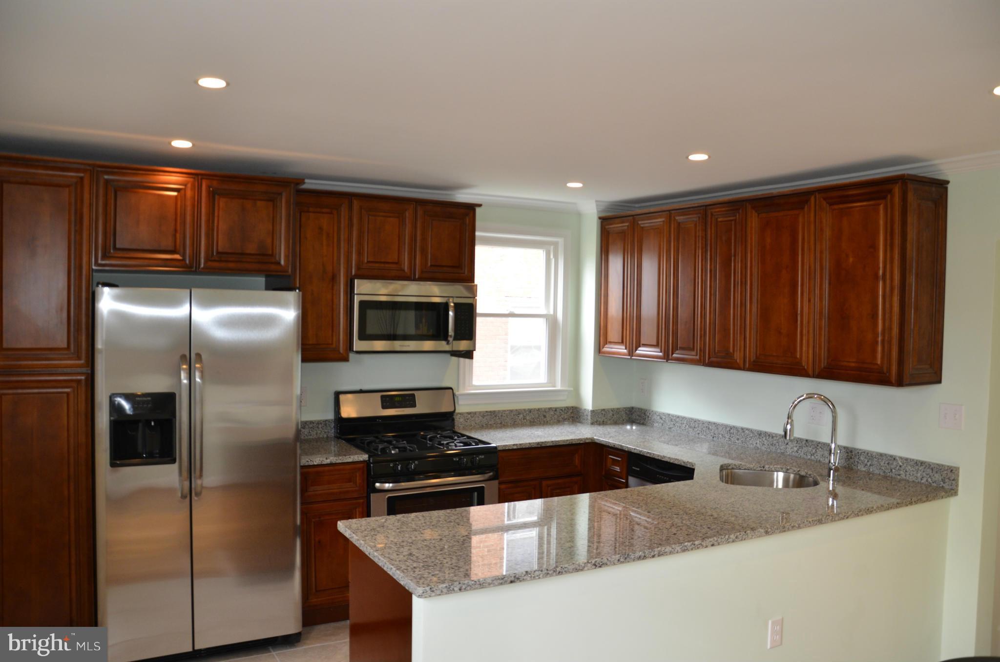 a kitchen with stainless steel appliances granite countertop a sink a stove a refrigerator a washer and dryer