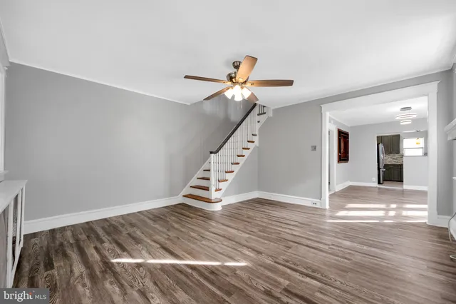 a view of an empty room with wooden floor and a ceiling fan