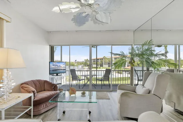 a living room with furniture a chandelier and a floor to ceiling window