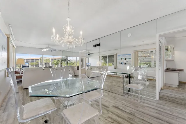 a dining room with wooden floor a chandelier a glass table and chairs
