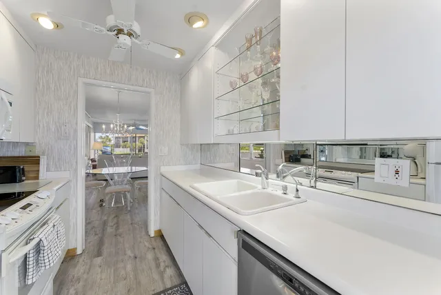a kitchen with a sink dishwasher stove and white cabinets with wooden floor