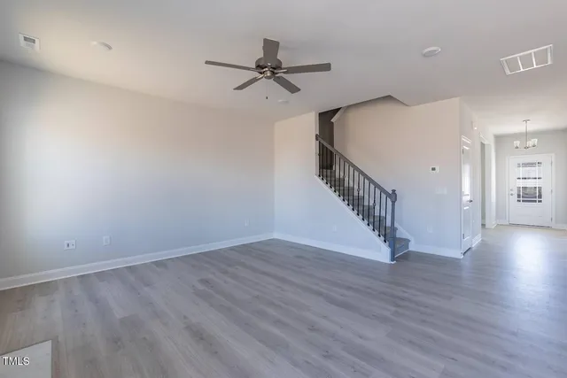 a view of a room with wooden floor ceiling fan and windows