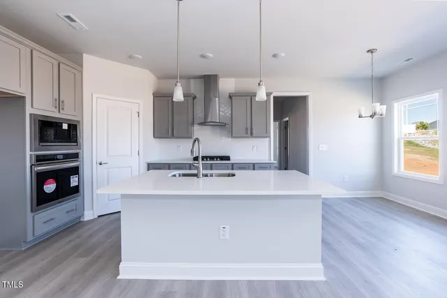 a large kitchen with stainless steel appliances granite countertop a sink a stove and a wooden floors