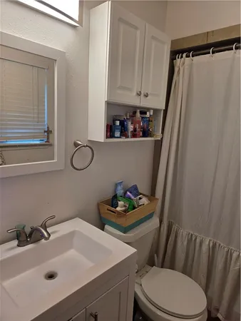 a bathroom with a sink a toilet and shower curtain