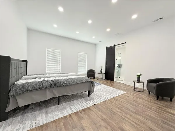 a spacious bedroom with a bed and wooden floor