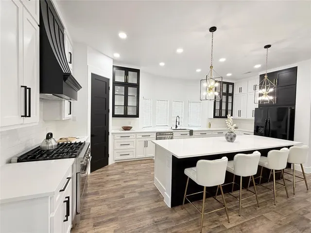 a kitchen with stainless steel appliances kitchen island granite countertop a sink a stove a refrigerator and cabinets