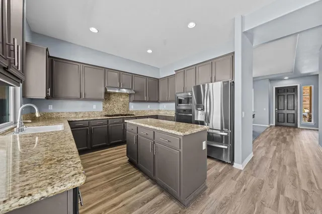a kitchen with granite countertop kitchen island wooden cabinets granite counter tops and a sink