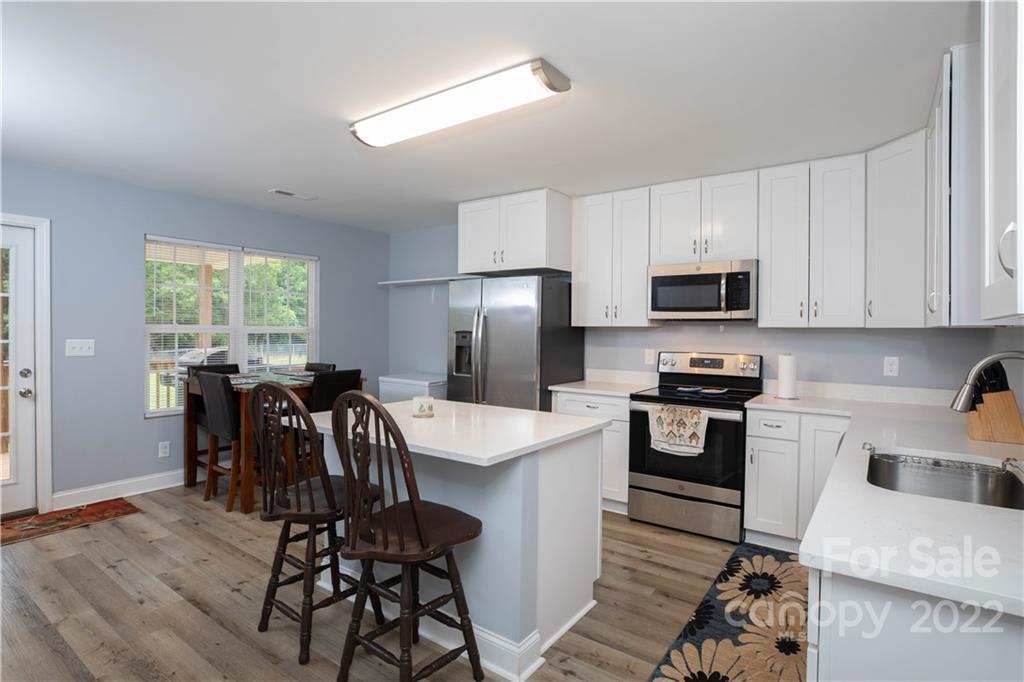 2993 Greenleaf Road Clover, SC 29710 - Photo 5 of 27 a kitchen with granite countertop a stove top oven a sink dishwasher a dining table and chairs with wooden floor