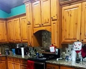 a kitchen with stainless steel appliances granite countertop a refrigerator a sink dishwasher a stove and white countertops with wooden floor