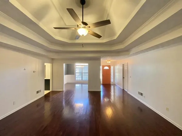 an empty room with wooden floor chandelier and windows