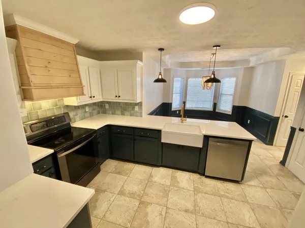 a kitchen with granite countertop white cabinets and stainless steel appliances