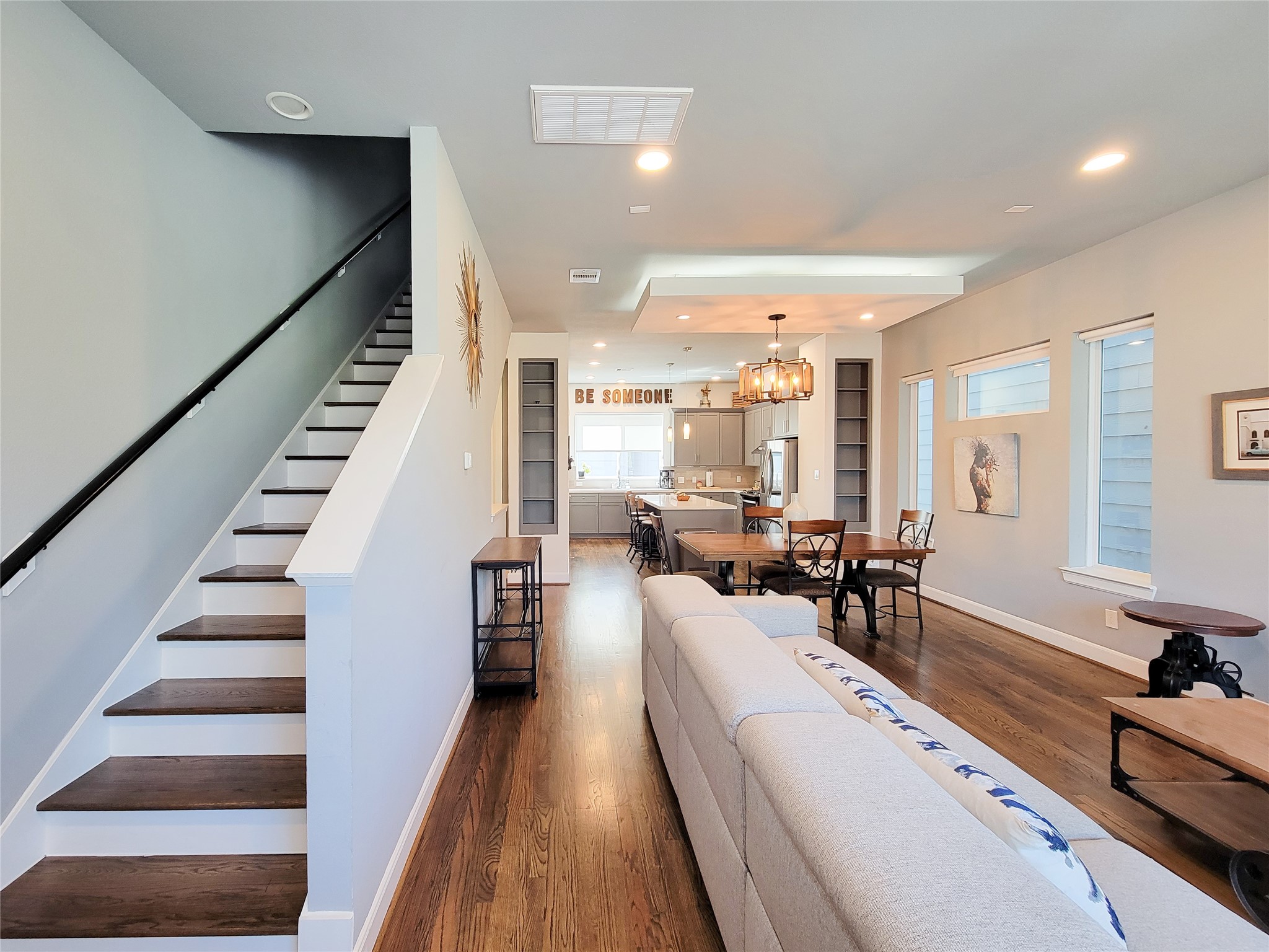 1705 Eado Point Lane Houston, TX 77003 - Photo 19 of 50 An open-concept living and dining area with modern decor. The room is well-lit with recessed lighting and has hardwood floors throughout, creating a warm and inviting atmosphere.