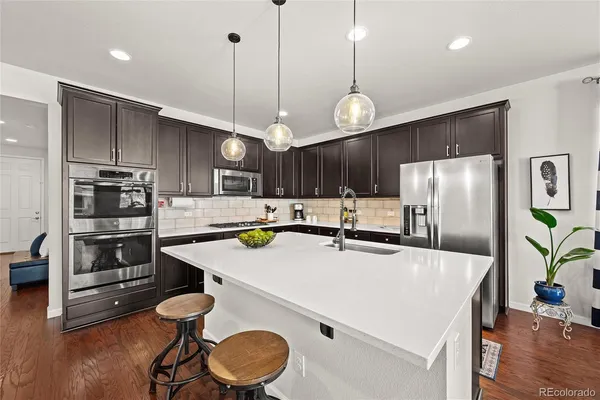 a kitchen with stainless steel appliances kitchen island a table chairs and microwave