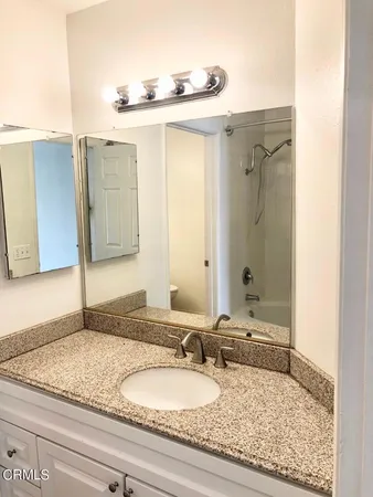 a bathroom with a granite countertop sink and a mirror