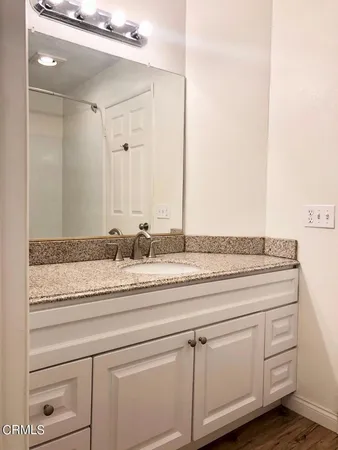 a bathroom with a granite countertop sink and white cabinets