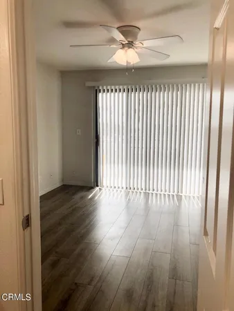 an empty room with wooden floor fan and windows