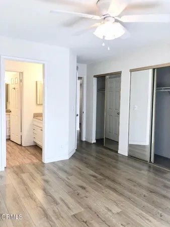 an empty room with wooden floor closet and windows