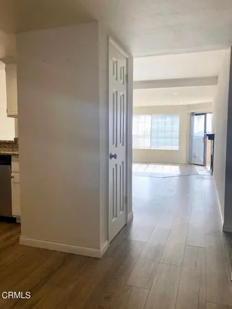 a view of a hallway with wooden floor and a living room