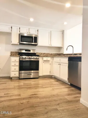 a kitchen with stainless steel appliances granite countertop a stove a sink and a microwave