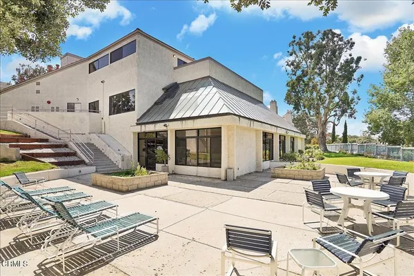 a view of a white house with a yard table and chairs