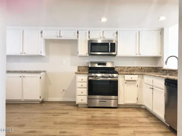 a kitchen with stainless steel appliances granite countertop a stove a sink and a microwave