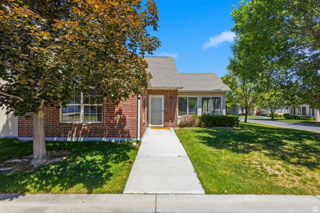 2047 West Abbey View Road, Unit 17C West Jordan, UT 84088 - Photo 1 of 50 Brick exterior with a gabled roofline, featuring a concrete walkway, mature trees, and established landscaping