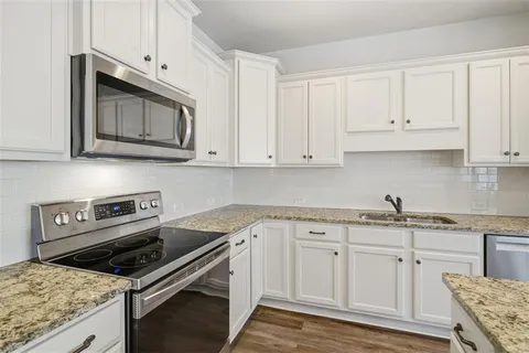a kitchen with granite countertop a stove sink and microwave